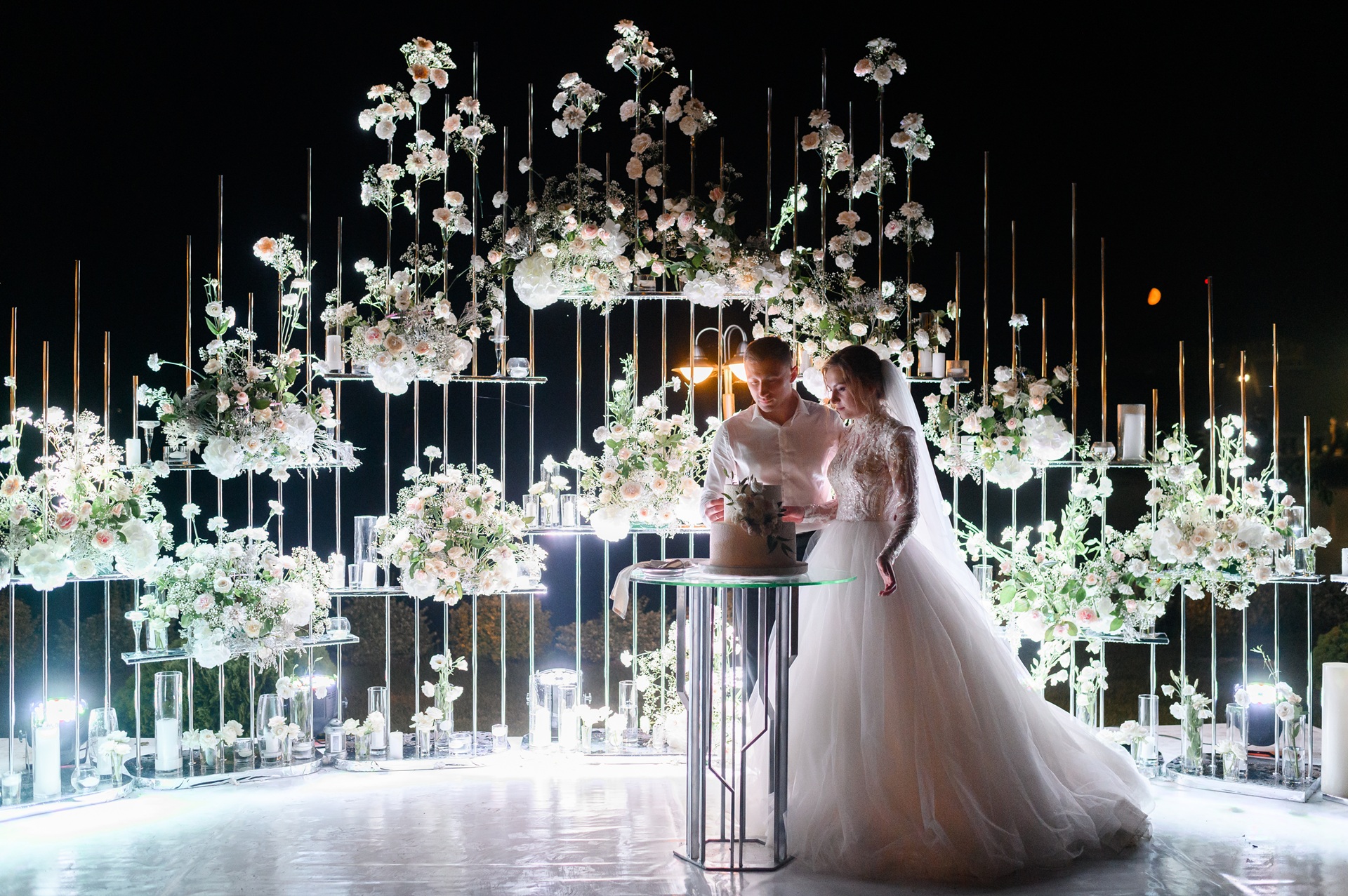 Event crew setting up a lighting rig against dramatic pink and gold stage uplighting