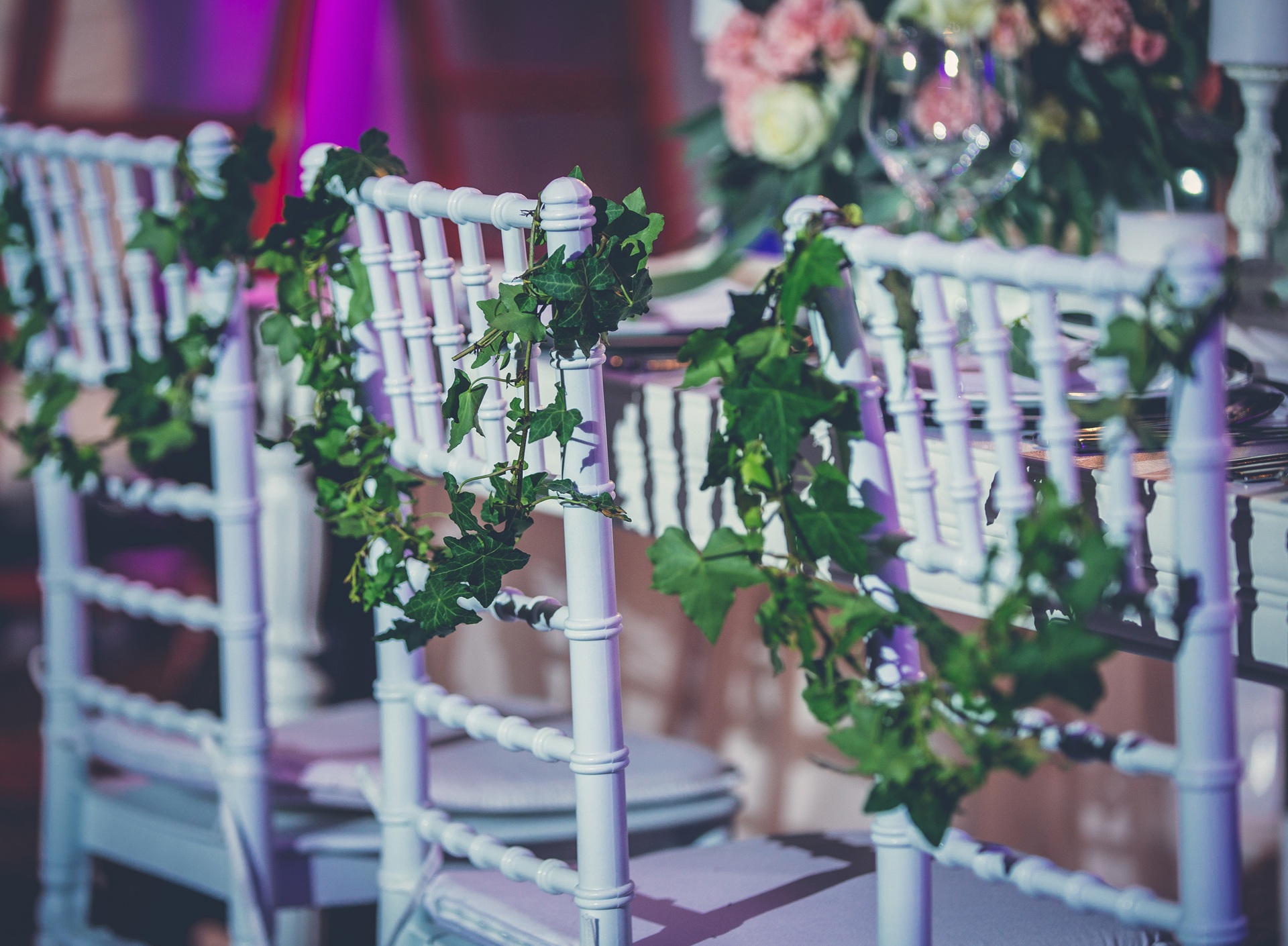 Chiavari chairs trailed with ivy garlands at a softly lit reception table setting