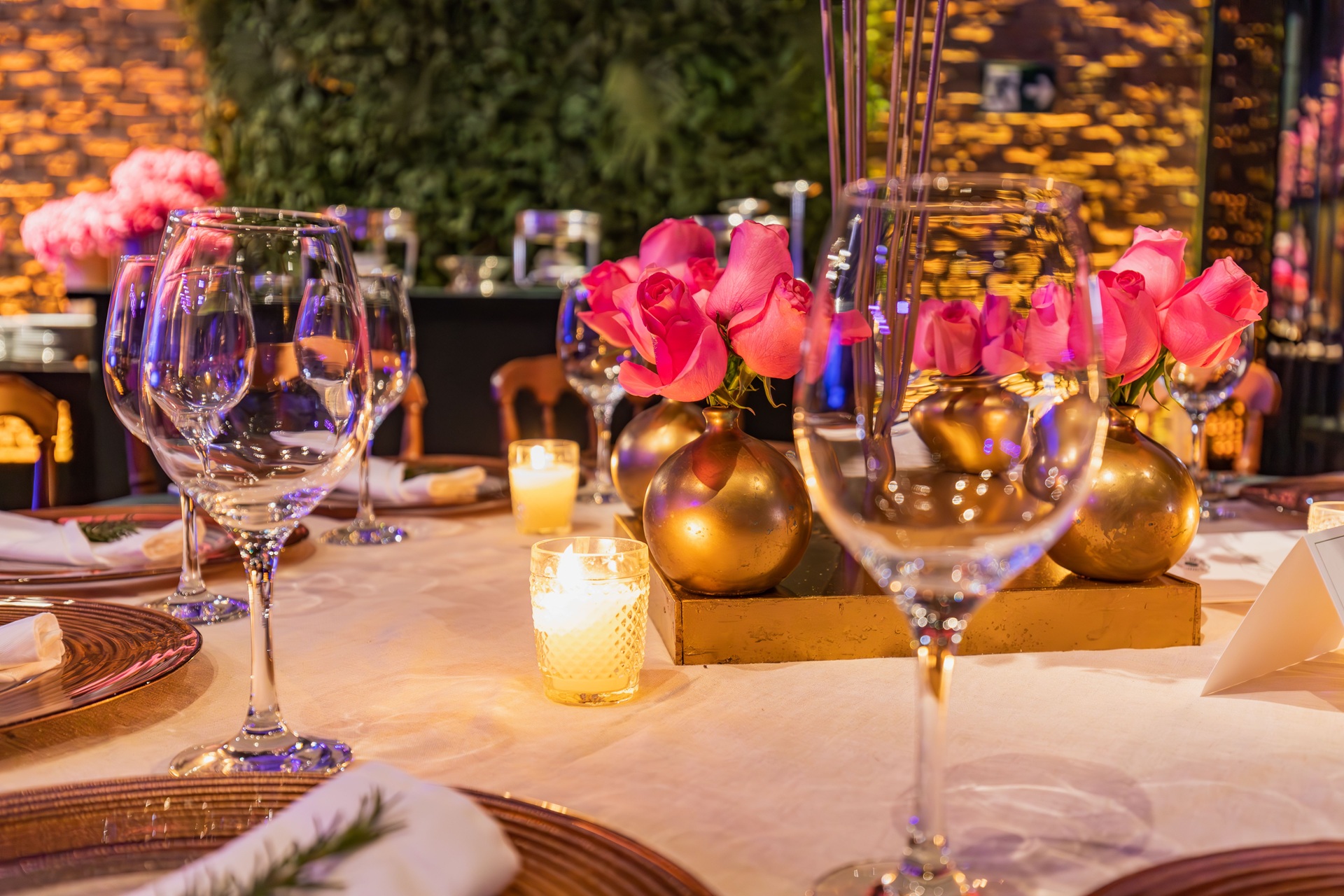 Intimate candlelit table setting with pink roses in gold bud vases